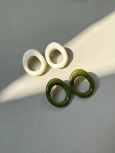 Detail of cream and olive green resin oval stud earrings with smooth glazed finish