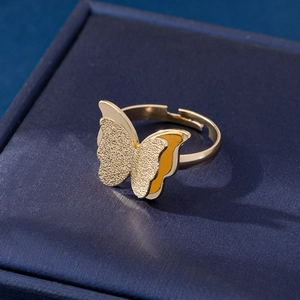 Close-up of golden double-layered butterfly ring with frosted texture on navy box