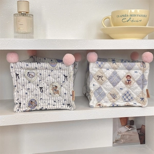 Detail of quilted fabric storage bins with bear patterns and pink pom-pom trim on shelves