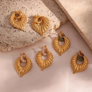 Detailed shot of gold leaf earrings with white rhinestones and green beads textures