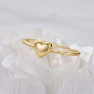 Macro shot of minimalist gold heart ring with zircon inlay on white petals