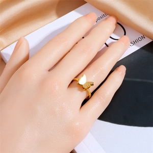 Elegant gold butterfly open ring with textured wings worn on hand against satin