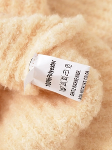 Détail de l'étiquette d'entretien sur cardigan beige en peluche avec instructions