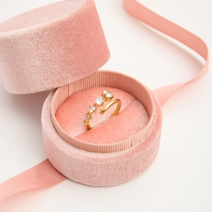Detail view of a gold zirconia open ring displayed in a pink velvet jewelry box