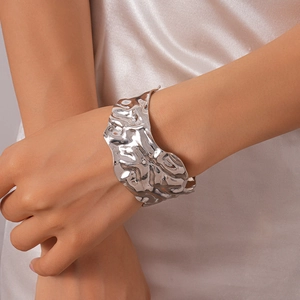 Détail d'un large bracelet manchette argenté martelé avec texture irrégulière sur le poignet