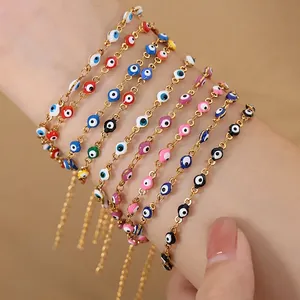 Bohemian gold chain bracelets with colorful evil eye charms worn on a female wrist
