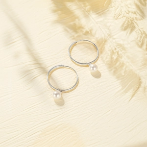 Macro view of silver metal hoop earrings featuring elegant white pearl pendants