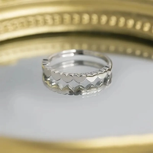Silver heart-shaped band ring displayed on a reflective mirror with elegant decor