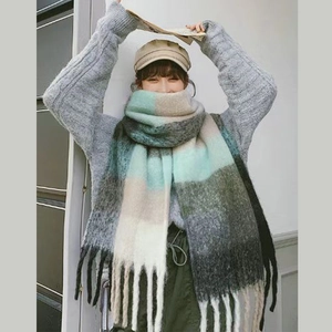 Detail of soft thick knitted rainbow scarf featuring stylish blue and beige tassels