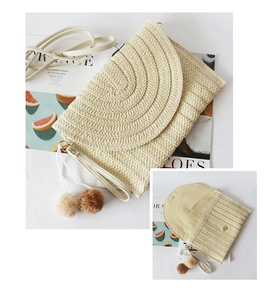 Detail view of woven straw envelope clutch featuring poms clutch with chic pom-poms and adjustable shoulder strap