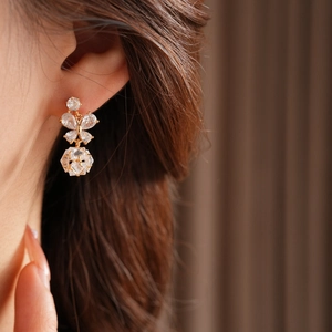 Détail de boucles d'oreilles papillon dorées avec cristaux et pendentif géométrique