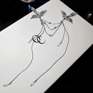 Detail of silver phoenix brooch featuring intricate feathers and pearl tassel fringe