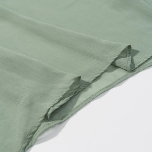 Detail shot of light green pleated chiffon fabric showing soft texture and stitching