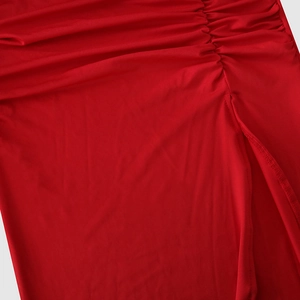 Close-up of red ruched dress detailing features textured fabric and side slit design