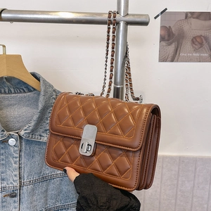 Detail of brown quilted leather bag with gold chain strap and metal turn-lock closure