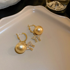 Detail of vintage gold pearl earrings with a sparkling rhinestone bow on a tray