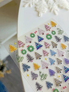 Détail macro de stickers ongles 3D en relief avec sapins et textures pailletées