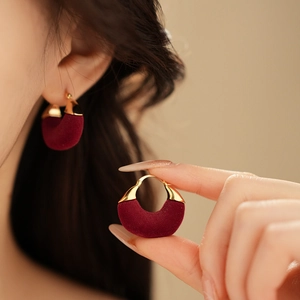 Detail of burgundy flocked U-shaped hoop earring with gold plating on female model