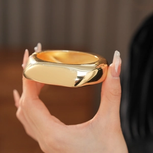 Close-up of irregular chunky gold metal cuff bracelet showing high-shine polished finish