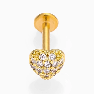 Close-up of golden heart-shaped labret piercing with clear zircon stones on white background