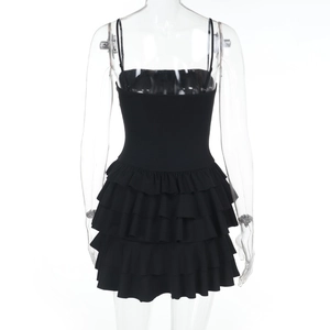 Detail view of the multi-layered ruffle hem on a black bodycon mini dress