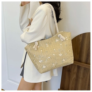 Détail du sac cabas en paille beige avec anses en corde blanche et broderie florale