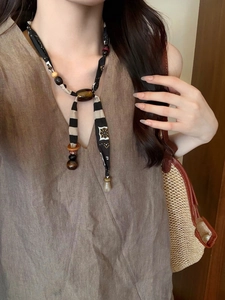 Detailed view of handmade fabric ribbon necklace with brown acrylic beads and geometric prints