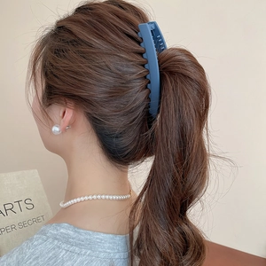 Détail de la pince à cheveux bleue mate fixant une queue de cheval avec des perles