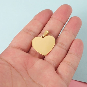 Polished gold heart pendant made of stainless steel displayed in a person's hand