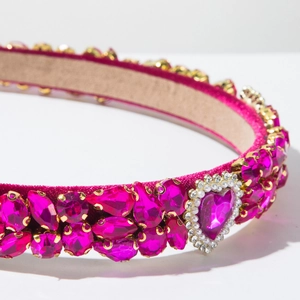 Detail van een barokke haarband met roze fluweel, luxe edelstenen en een parelhartje