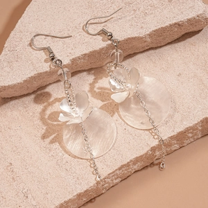 Detail of shell flower tassel earrings with glass beads on natural stone background