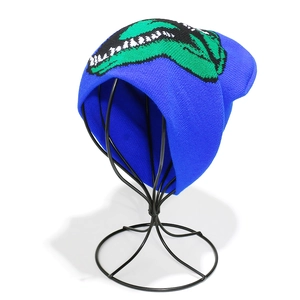 Detail view of the ribbed knit fabric and green dinosaur teeth pattern on the blue beanie