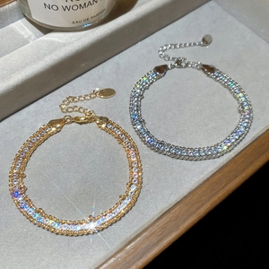 Close-up of gold and silver rhinestone chain bracelets on a jewelry display tray