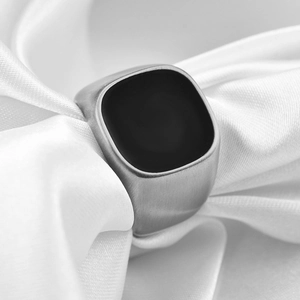 Detailed view of matte silver ring with black enamel inlay on white satin background