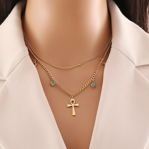 Double-layered gold necklace with blue rhinestones and an Ankh cross pendant on a model