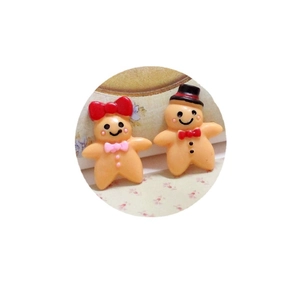Pair of DIY resin gingerbread man charms with painted bows and hats for holiday crafts