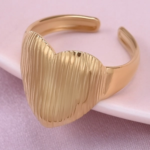 Macro d'une bague coeur dorée avec texture à rayures verticales et anneau ajustable