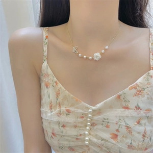 Elegant gold necklace with white rose pendant, pearl accents, and sparkling diamond butterfly