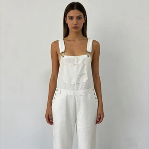Detail of white denim overalls showing classic large pockets and side metal button closures