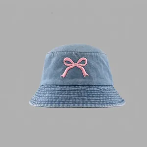 Close-up of pink bow embroidery on blue denim bucket hat with reinforced brim stitching