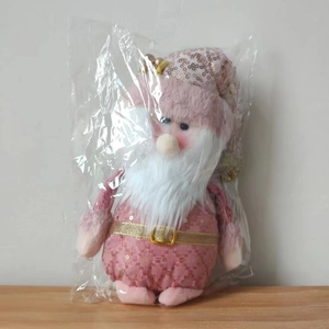 Close-up of pink plush Santa Claus doll with sequins and white beard in clear packaging