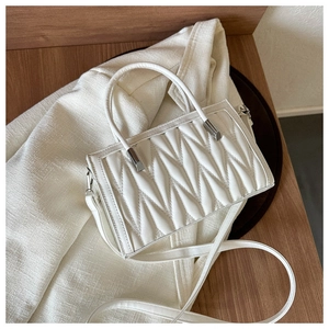 Detailed view of white pleated handbag showing 3D texture and silver hardware details
