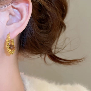 Detail view of retro resin round hoop earring with vintage textured metal finish on a model