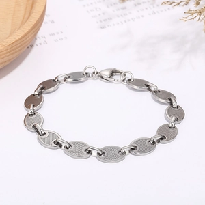 Detail showing silver hollow coffee bean link bracelet on a minimalist white table