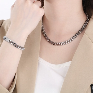 Vue détaillée d'un ensemble collier et bracelet gourmette argenté porté par un mannequin