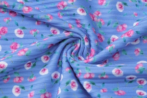 Nahaufnahme von blauem Rippenstoff mit rosa Blumendruck und weicher Strickstruktur