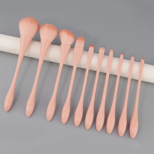 11-piece coral pink makeup brush set with ergonomic handles on a grey background