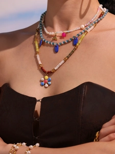 Close-up of layered bohemian beaded necklace with natural stones and flower pendant