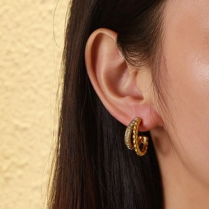 Detail of vintage gold titanium earrings with white zircon and beaded texture on model