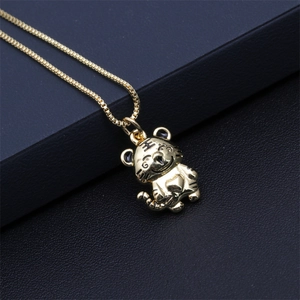 Close-up of gold-plated tiger pendant necklace with box chain on dark background